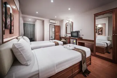 a hotel room with two beds and a television at KC Place Hotel Pratunam in Bangkok