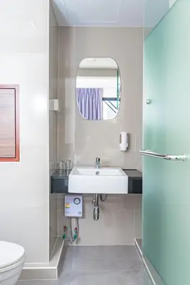 a bathroom with a sink and a toilet and a mirror at Sovereign Group Hotel at Pratunam in Bangkok