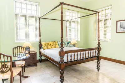 a bedroom with a four poster bed and a table at Baan 2459 Heritage House in Bangkok