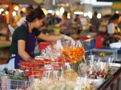 a woman standing in a market with a buffet of food at 28 Place in Bangkok