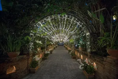 a hallway of an indoor garden with plants and lights at Chakrabongse Villas in Bangkok