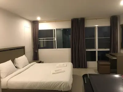 a bedroom with a bed and a desk and windows at S.E.T Thanmongkol Residence in Bangkok