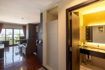 a bathroom with a sink and a living room at Mida Hotel Don Mueang Airport in Bangkok