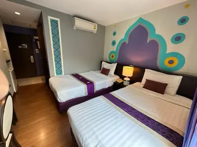 a hotel room with two beds and a painting on the wall at Sawasdee Hotel @ Sukhumvit Soi 8 in Bangkok