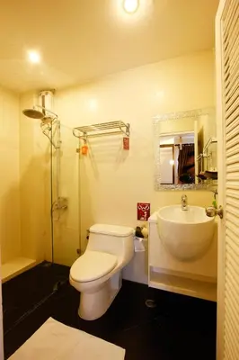 a bathroom with a toilet and a sink and a mirror at Mirth Sathorn Hotel in Bangkok