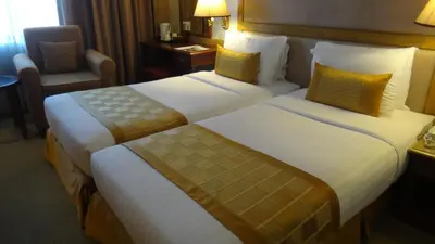 a hotel room with two beds and a chair at Arnoma Hotel Bangkok in Bangkok