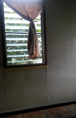 a window with a curtain in a room at Anurak Guesthouse in Bangkok