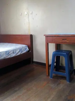 a room with a desk and a stool next to a bed at Anurak Guesthouse in Bangkok