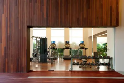 a fitness room with a gym with a large window at Hansar Bangkok Hotel in Bangkok