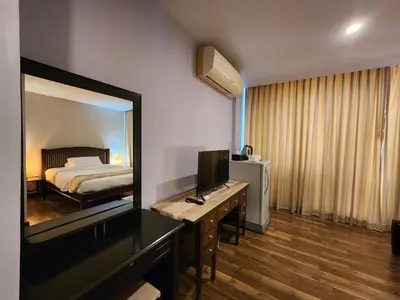 a hotel room with a bed and a desk with a television at August Residence in Bangkok