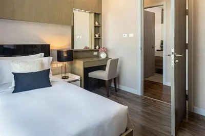 a bedroom with a bed and a desk with a chair at Metropolis Suites Bangkok, Tapestry Collection by Hilton in Bangkok