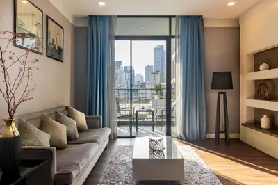 a living room with a couch and a large window at Metropolis Suites Bangkok, Tapestry Collection by Hilton in Bangkok