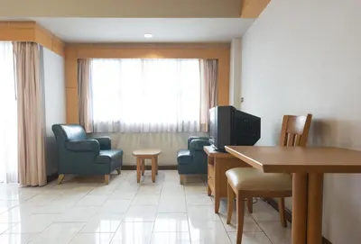 a waiting room with chairs and a table and a television at Baan Pratoom in Bangkok