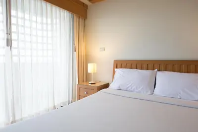 a bedroom with a large white bed with a window at Baan Pratoom in Bangkok