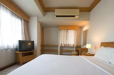 a bedroom with a white bed and a television at Baan Pratoom in Bangkok