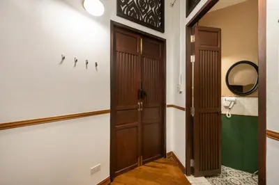 a hallway with two wooden doors and a mirror at Arun Sa Wad 103 NaNa in Bangkok