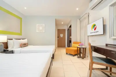 a hotel room with two beds and a desk at Hotel De Bangkok in Bangkok