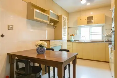 a small kitchen with a wooden table and chairs at Artisan's Antique House - Silom in Bangkok