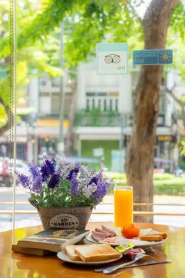 a table with a plate of food and a vase of flowers at For You Residence in Bangkok
