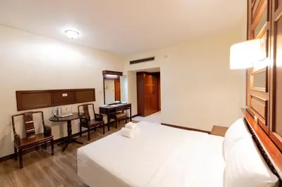 a bedroom with a bed and a desk with a piano at MIDO Hotel in Bangkok