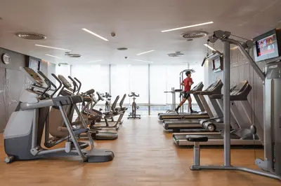 a gym with rows of treadmills and a man in the background at Four Points by Sheraton Bangkok Ploenchit Sukhumvit in Bangkok