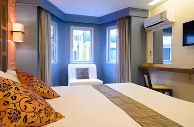 a hotel room with a bed and a chair at Golden House in Bangkok