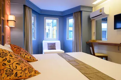a hotel room with a bed and a chair at Golden House in Bangkok