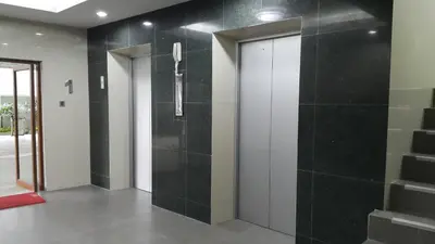 a hallway with black tile walls and a elevator at The Supara in Bangkok