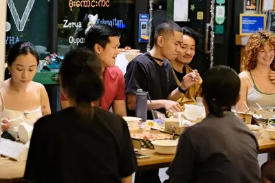 a group of people sitting around a table eating food at Wayha Hostel Don Mueang Airport in Bangkok