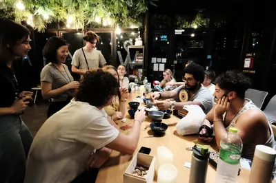 a group of people sitting around a table at Wayha Hostel Don Mueang Airport in Bangkok