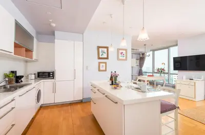 a kitchen with white cabinets and a kitchen island at Sky Villas Apartments in Bangkok