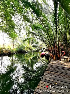 a wooden bridge over a body of water with palm trees at Baan Glangsuan Bang Kobua in Bang Chak