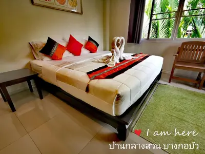 a bedroom with a bed with pillows at Baan Glangsuan Bang Kobua in Bang Chak