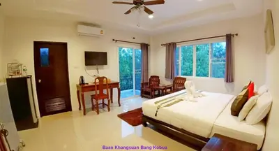 a bedroom with a bed and a desk in it at Baan Glangsuan Bang Kobua in Bang Chak