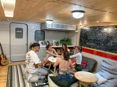 a group of people sitting in a living room in a trailer at Tales Khaosan (Cafe & Hostel) in Bangkok