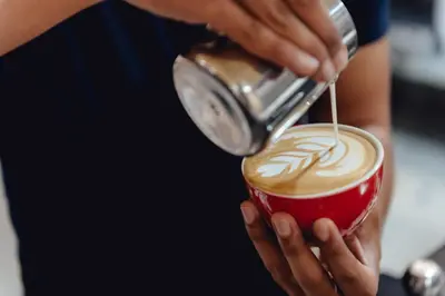 a person is pouring milk into a cup of coffee at Tales Khaosan (Cafe & Hostel) in Bangkok