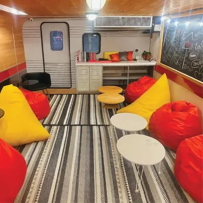 a rv with two tables and yellow and red cushions at Tales Khaosan (Cafe & Hostel) in Bangkok
