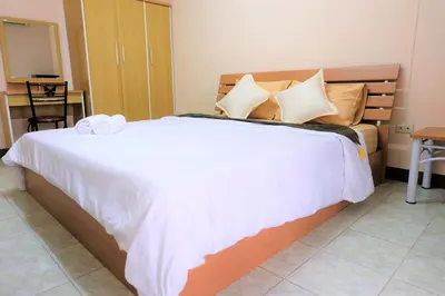 a bedroom with a large bed with white sheets and pillows at Goody Hotel in Bangkok