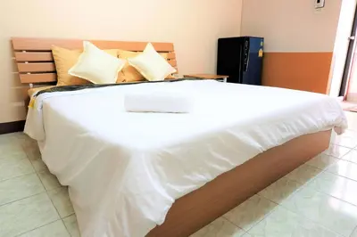 a large bed with white sheets and pillows at Goody Hotel in Bangkok