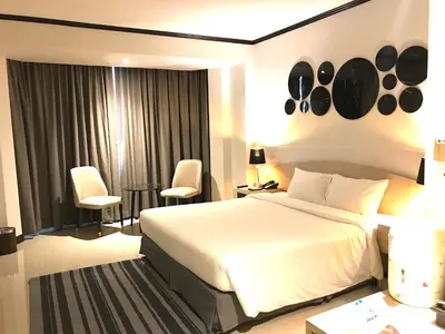 a bedroom with a large white bed and chairs at The Maruay Garden Hotel in Bangkok