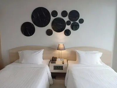 two beds in a room with a clock on the wall at The Maruay Garden Hotel in Bangkok