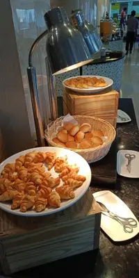 a table with plates of pastries and baskets of bread at The Maruay Garden Hotel in Bangkok