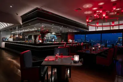 a restaurant with tables and a bar with a view at The Landmark Bangkok in Bangkok