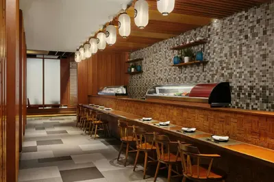 a restaurant with a long bar with stools at Jubilee Prestige Hotel Ratchadapisek in Bangkok