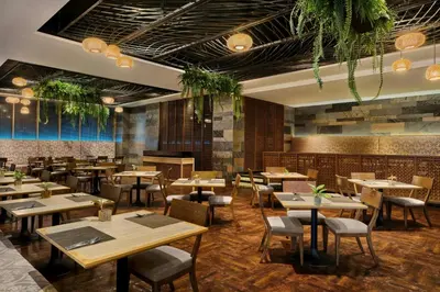a restaurant with wooden tables and chairs and plants at Jubilee Prestige Hotel Ratchadapisek in Bangkok