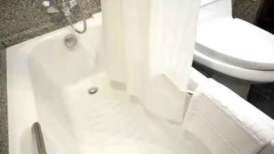 a bathroom with a toilet and a bathtub with a shower curtain at Majestic Suites Hotel in Bangkok