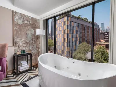 a bath tub in a bathroom with a large window at Pipa Hotel Bangkok Sukhumvit 11 in Bangkok