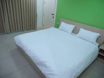 a large white bed in a room with a green wall at Baan mek mok in Bangkok