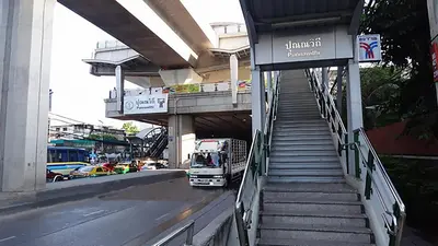 a truck driving down a city street with a bridge at Baan mek mok in Bangkok