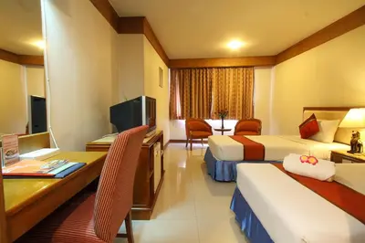 a hotel room with two beds and a desk at Silom Avenue Inn in Bangkok